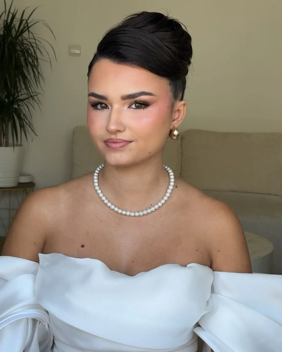 Mariee en chignon haut, collier de perles et bustier clair