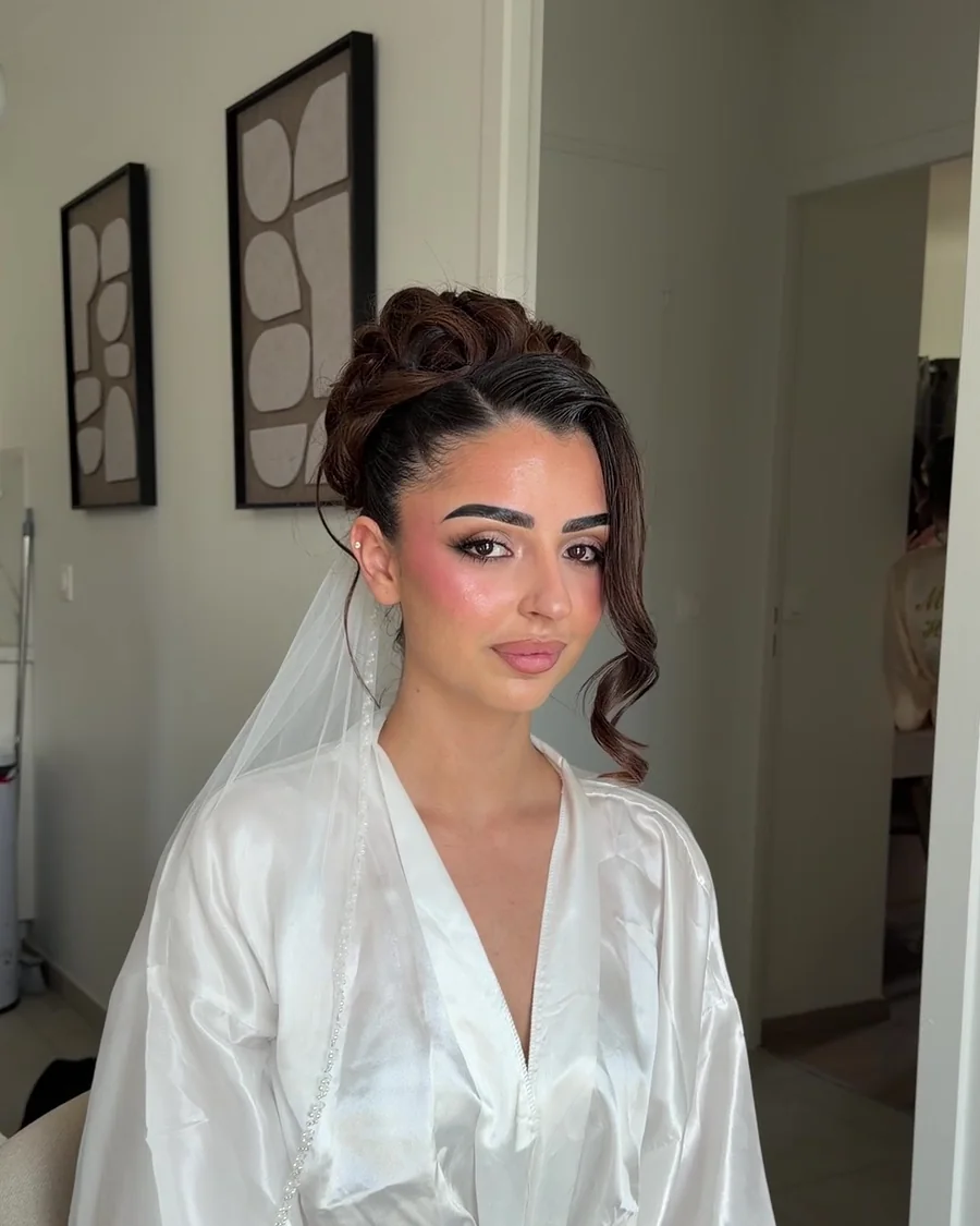 Une mariee en peignoir et voile, maquillage termine, avant d'enfiler sa robe