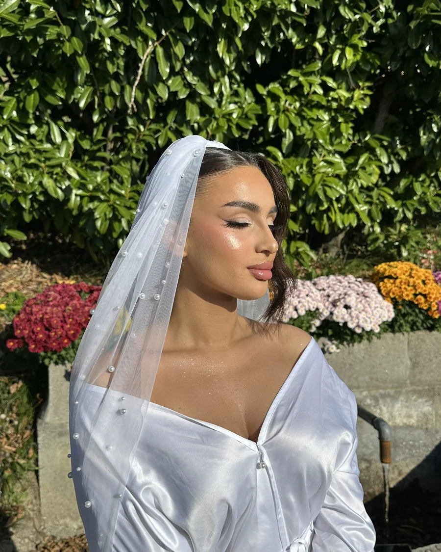 Mise en beaute de mariee sous un voile a perles, dans un jardin
